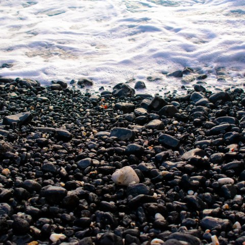 Pebble beach with sea waves lapping the shore.