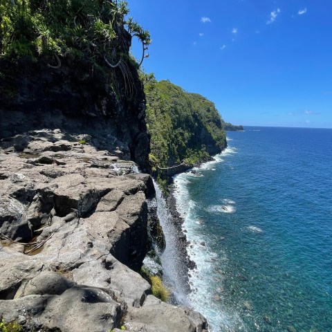 Rocky cliffside with ocean view and blue sky.