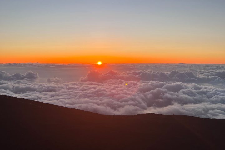 Sunset over clouds from a mountain top horizon view.