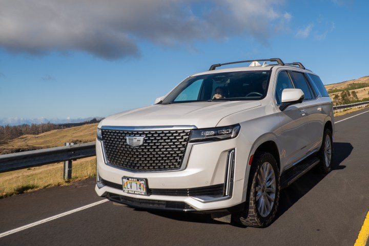 White SUV parked on a scenic rural road with cloudy sky.